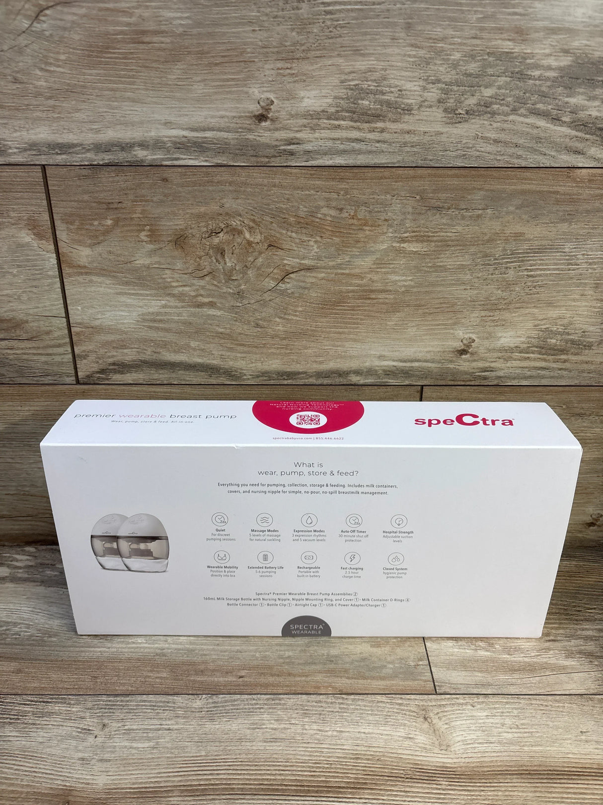 Front view of Spectra Premier wearable electric breast pump box showing product image and feature icons on wood background