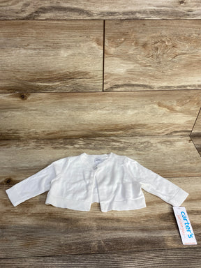 White long-sleeve baby cardigan from Carter's with single button and tag on wood background