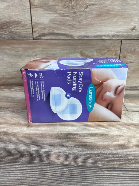 Front view of Lansinoh Stay Dry Nursing Pads showcasing 100 pads and absorbent pad design on a wood floor