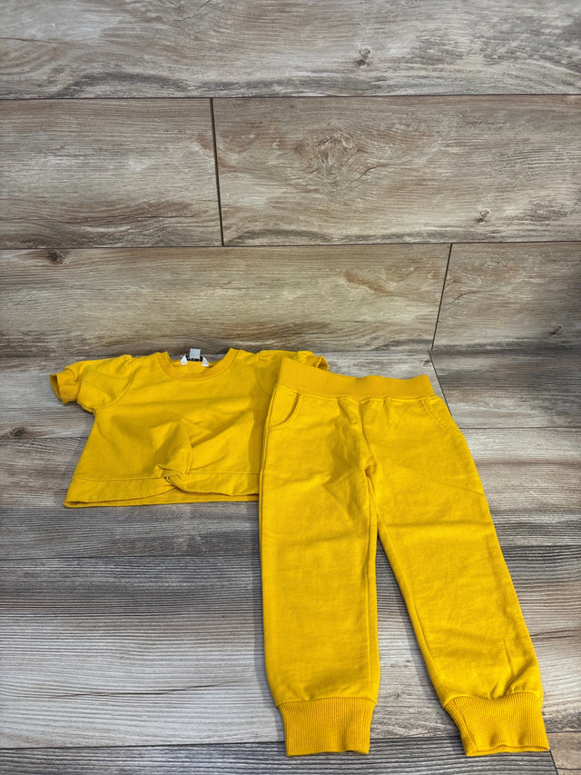 Bright yellow toddler outfit: short-sleeve top with front knot and matching jogger pants on wood floor
