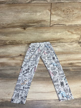 Flat lay of grey toddler leggings showcasing black music-themed doodle print with small pink and blue accents on a wood floor background