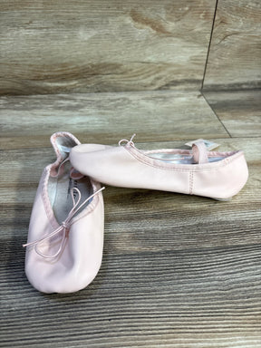 Light pink ballet slippers with bows on wooden floor
