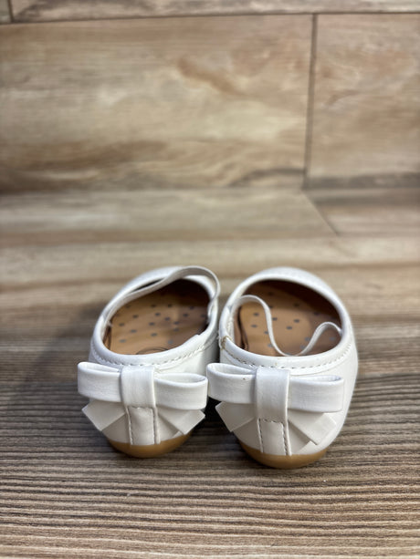 Rear view of white girls' ballet flats (size 2C) showing bow detail on the heels against a woodgrain floor