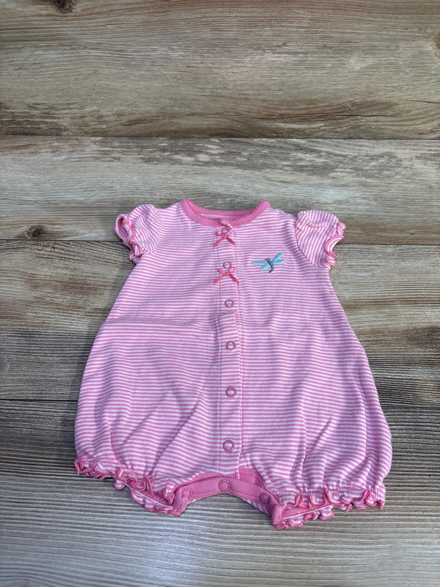 Front view of Simple Joys pink striped shortie romper with button-front closure, ruffle sleeves and bird embroidery on wood