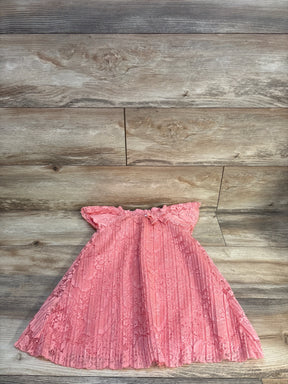 Pink lace baby dress with ruffled sleeves and pleated skirt on wood floor
