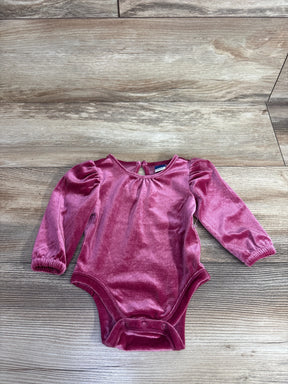 Plush pink velvet long sleeve baby bodysuit with snap closures on wooden floor