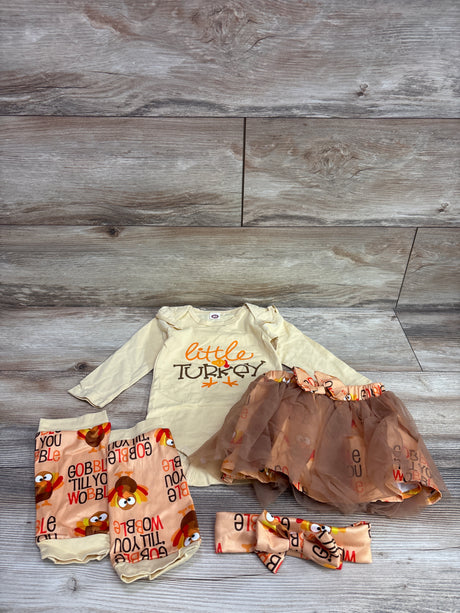Flat lay of yellow Little Turkey 4-piece set showcasing a bodysuit, turkey-print skirt, leg warmers, and headband