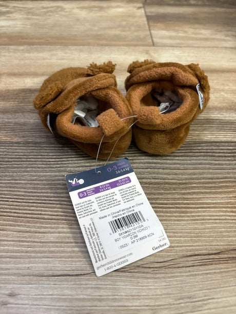 Top view of brown Gerber fleece lined non skid soft slipper booties showcasing soft cuffs on a wood grain background