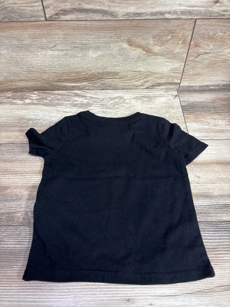 Back view of a plain black short sleeve t-shirt for a toddler size 2T on a wooden floor.