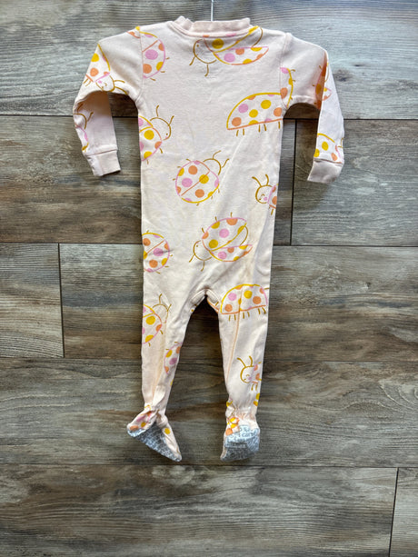 Front view of Carter’s peach sleeper showcasing long sleeves, covered feet, and colorful ladybug print on a wood background