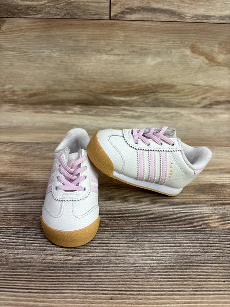 Angled view of Adidas Samoa I sneakers in white with pink laces, pink stripes, and gum soles on a wood background