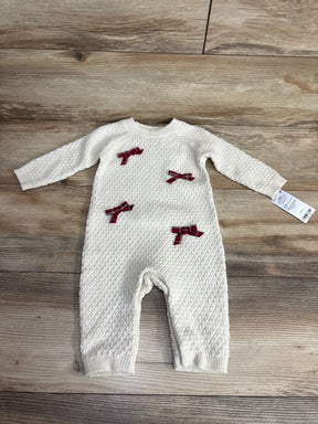 White knit baby onesie with red plaid bows, 6 months, laid on wood floor