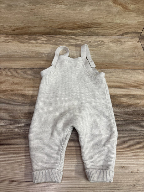 Flat lay of grey Little Planet knit overalls, size 3 months, with shoulder straps and ribbed cuffs on a wood floor