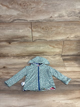 Flat lay of reversible baby hoodie showing front zipper, hood, and small white floral print on blue fabric on wood floor