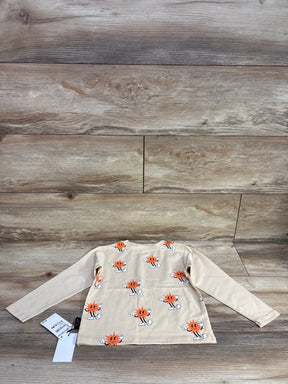 Beige long-sleeve children's shirt with orange sun cartoon print on wood background