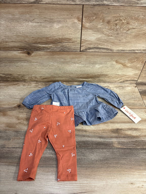 Baby girl outfit with blue long sleeve top and orange floral leggings on wood background