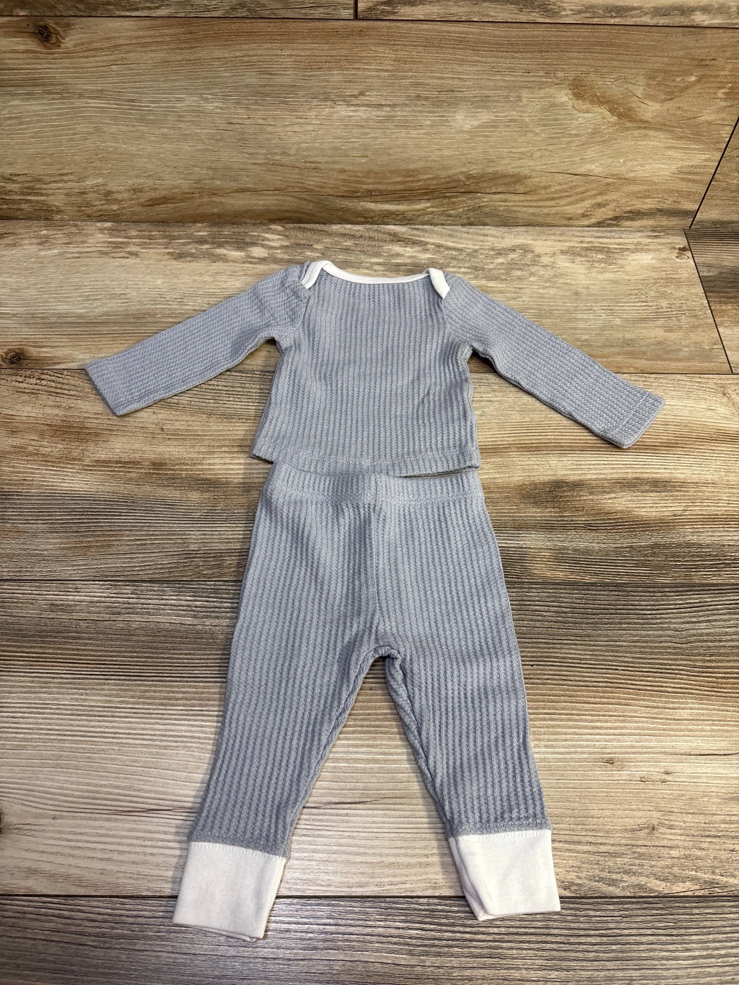Top-down view of Cloud Island grey textured newborn shirt and pants set with white cuffs and collar on a wooden background