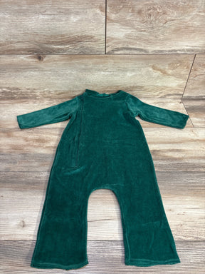 Green velvet baby romper with long sleeves laid flat on wooden floor