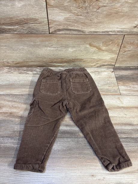Back flat lay of Old Navy brown corduroy pants size 12-18 months showing elastic waistband and patch back pockets on wood floor