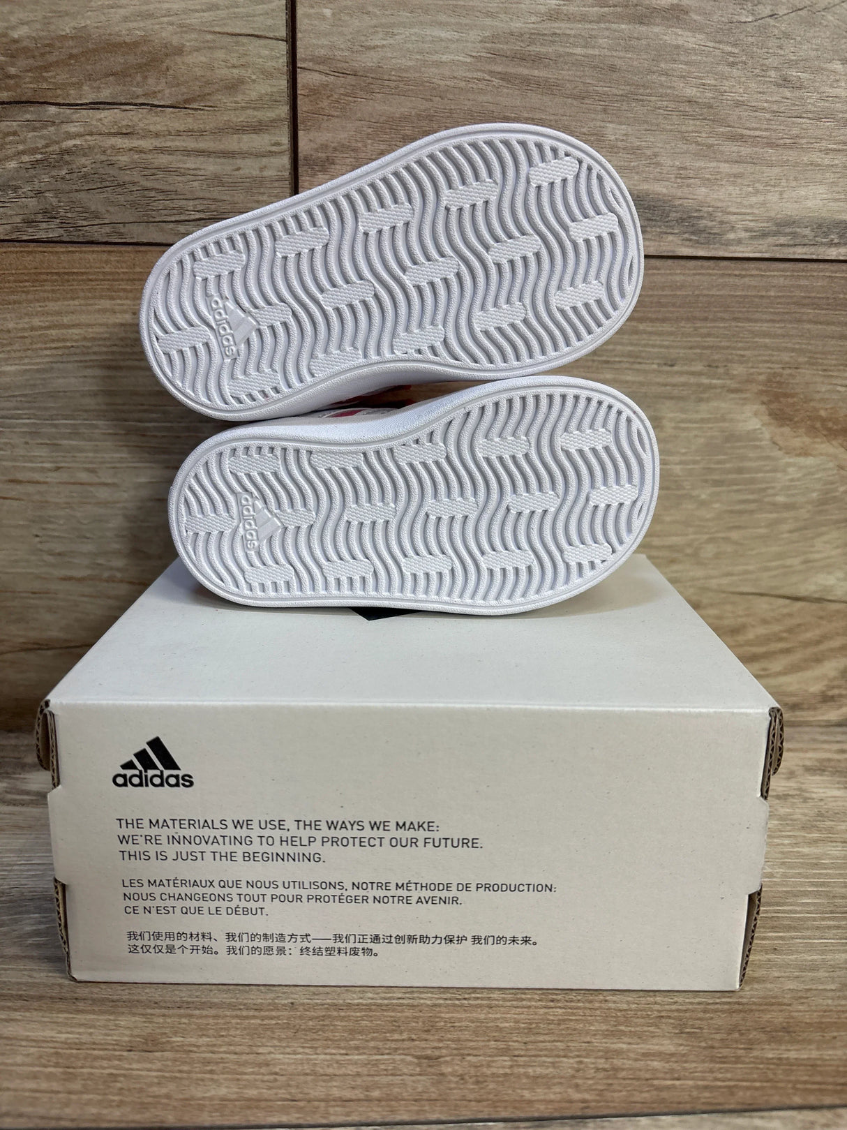 White Adidas toddler sneakers with wave-pattern soles, displayed on box, ideal for kids' footwear resale.