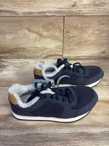 Side view of Cat & Jack toddler sneakers, navy blue, lace-up, gray fleece lining, white midsole, tan heel patch on wood