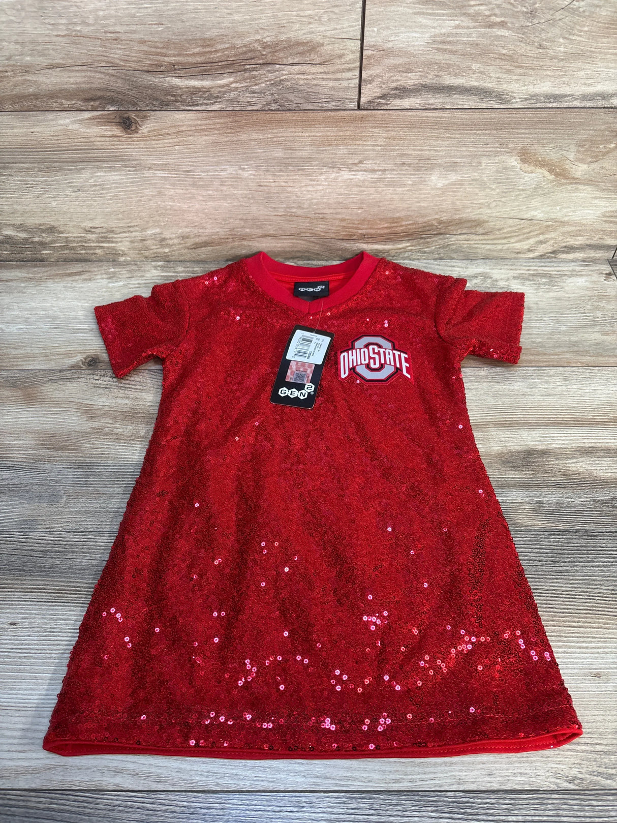 Red sequined toddler dress with Ohio State logo, laid flat on wood floor.