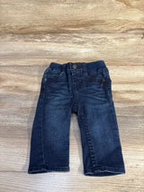Front view of Levi's navy baby skinny jeans, size 6 months, showing ribbed elastic waistband, faded dark wash, faux button fly on wood floor