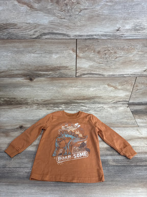 Brown long sleeve kids shirt with stegosaurus dinosaur and 'Roar Some' text on wood background