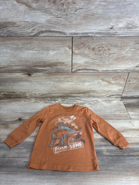 Brown long sleeve kids shirt with stegosaurus dinosaur and 'Roar Some' text on wood background