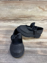 Front and side view of Cat & Jack Kori Mary Jane flats, black glitter, showing lug sole tread and grosgrain bow on light wood