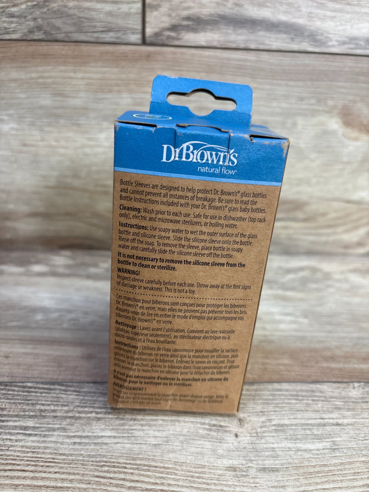 Rear view of Dr. Brown's Options+ 8oz narrow glass bottle sleeve box showing instructions and blue logo on wood background