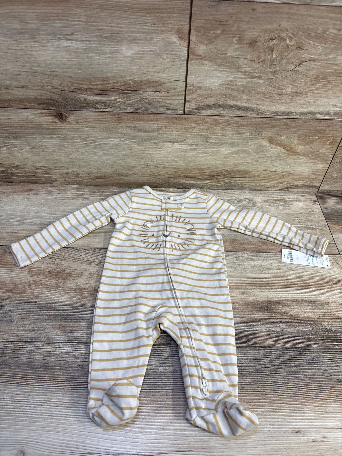 Front view of Carter’s beige striped sleeper in size 3 months, showcasing long sleeves and built-in footies on a wood floor