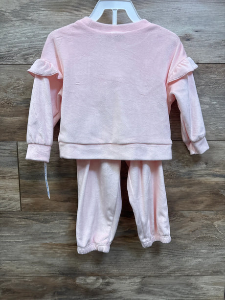 Back view of Carter’s 2-piece pink velvet sweatshirt and joggers set with ruffle sleeves on a wood background