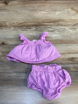 Light purple baby girl outfit with ruffle top and matching bloomers on wood background