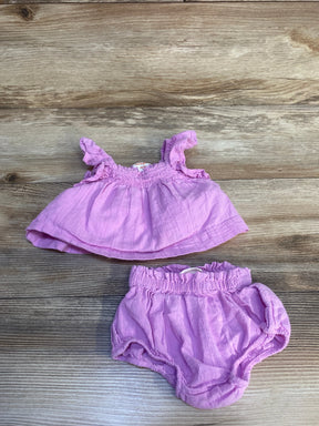 Light purple baby girl outfit with ruffle top and matching bloomers on wood background