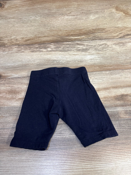 Top-down view of navy H&M toddler bike shorts (size 4T) showing elastic waistband and mid-thigh length on wood floor