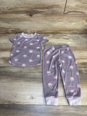 Purple floral toddler pajama set with short sleeves and elastic waist pants on wood floor