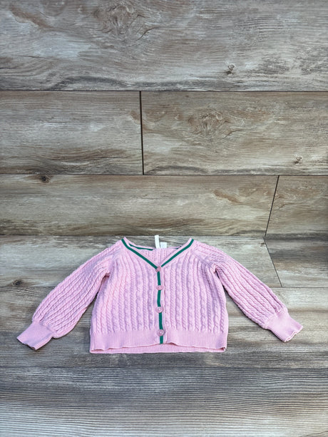 Front flat-lay of Janie and Jack pink cable-knit cardigan with balloon sleeves, green trim and buttons on wood backdrop