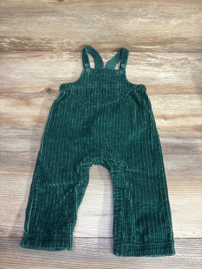Dark green corduroy baby overalls with adjustable shoulder straps laid on wooden background