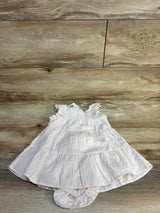 Pink and white striped baby dress with ruffles, laid on wood floor