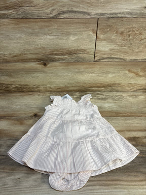Pink and white striped baby dress with ruffles, laid on wood floor