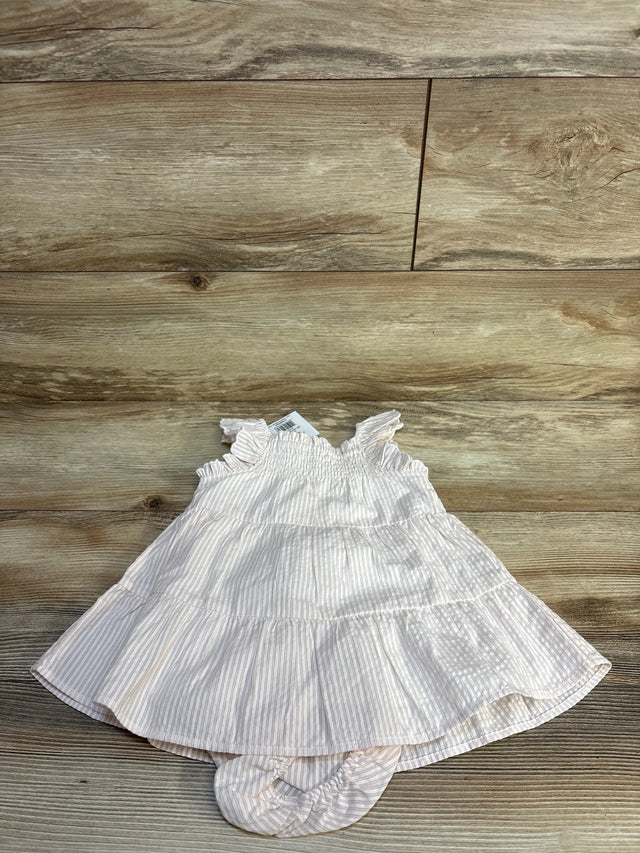 Pink and white striped baby dress with ruffles, laid on wood floor