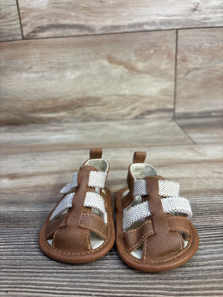 Front view of Cat and Jack tan soft-sole baby sandals showcasing white woven straps and brown faux-leather upper on woodgrain background