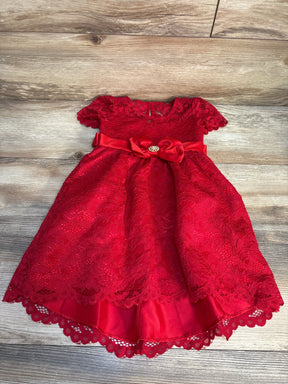 Red lace baby dress with short sleeves, satin bow, and jeweled accent on wooden floor