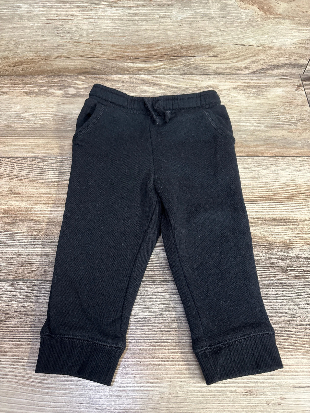 Black toddler jogger pants with elastic waistband and pockets on wooden background