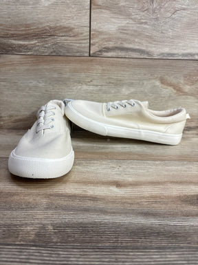 Pair of cream canvas sneakers with white rubber soles on wood floor