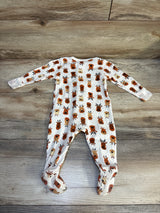 Baby footed sleeper with brown and orange reindeer print, laid flat on wood floor