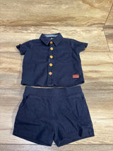 Front view of 7 For All Mankind navy 2pc button-up shirt and shorts set with chest pockets and gold buttons on wood background