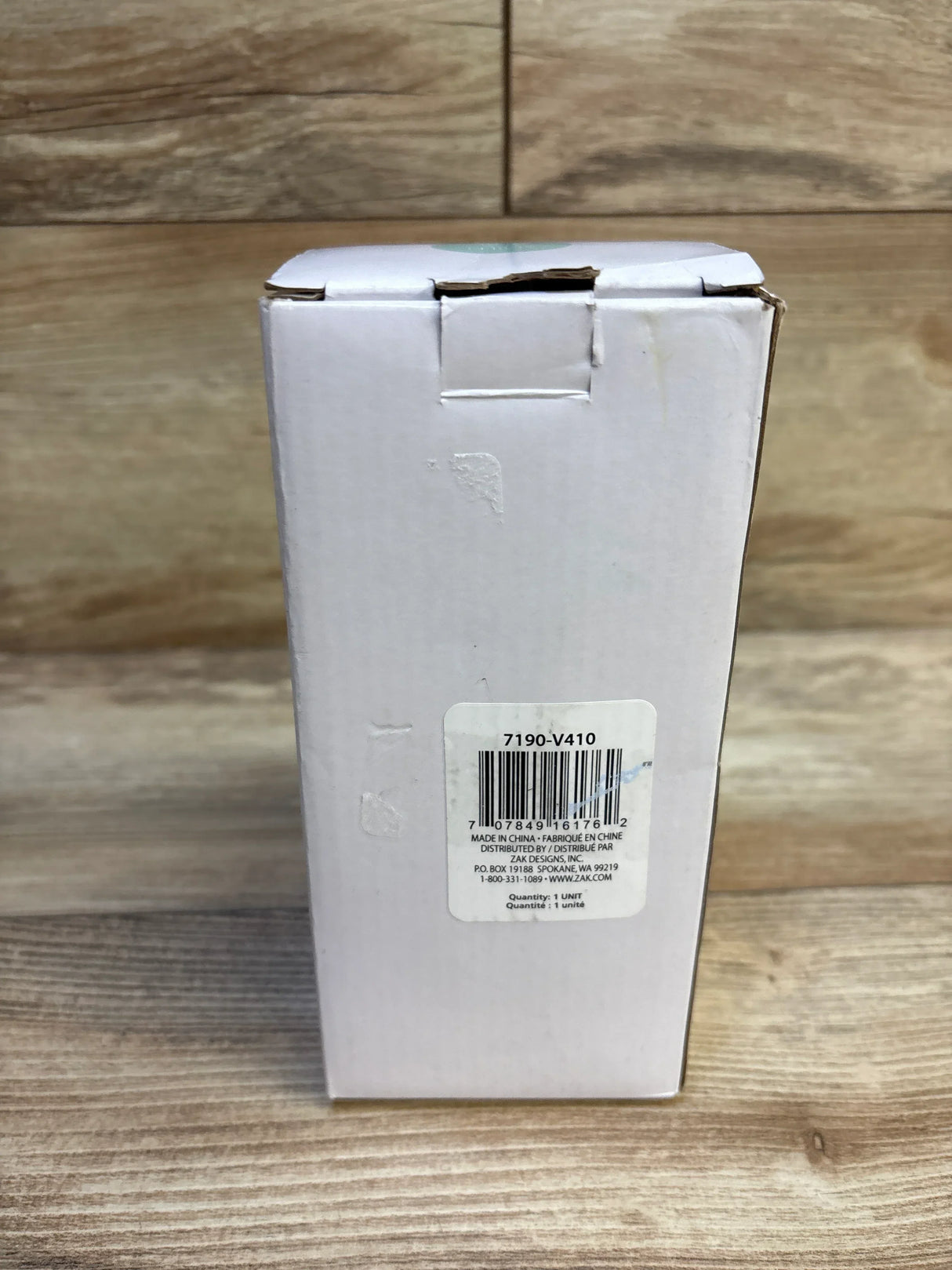 Rear view of boxed Zak Kelso insulated tumbler (Fanciful Unicorn, 12 oz) showing barcode sticker on white box on wood tabletop