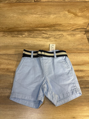 Light blue toddler shorts with black striped belt on wood background